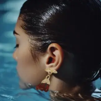 Female model wearing vintage yellow gold chandelier earrings in a swimming pool.