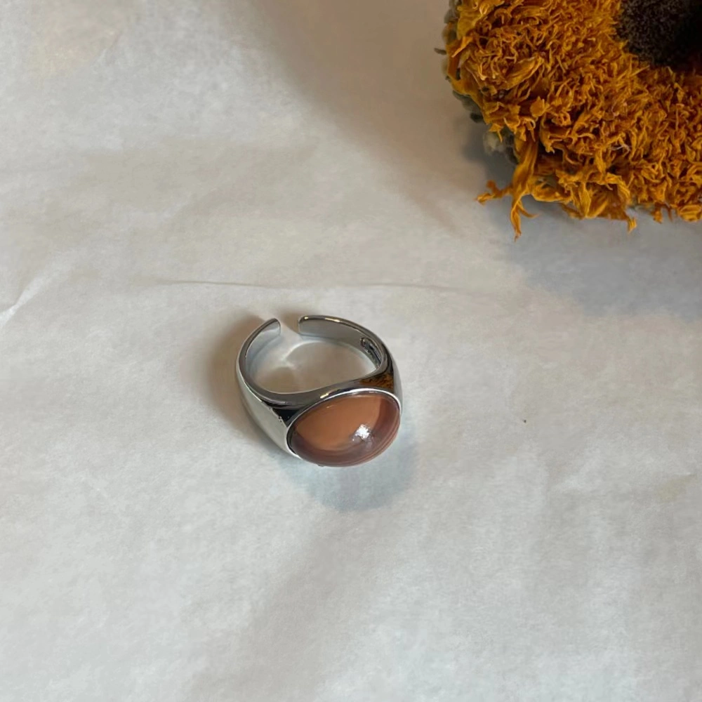 Honey jade stone alloy open ring on white paper with a dry sunflower in the background.