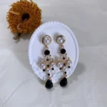 Vintage black & white 14K gold-plated long drop earrings displayed on white plaster with a dried sunflower in the background.
