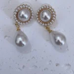 Vintage baroque pearl floral 14K gold-plated drop earrings placed on white plaster board.