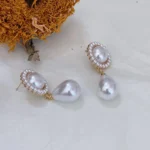 Vintage baroque pearl floral 14K gold-plated drop earrings placed on white fabric with a dried sunflower behind.