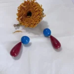 Vintage 14K gold-plated red and blue color block geometric earrings placed on white fabric with a dried sunflower behind.