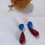 Vintage 14K gold-plated red and blue color block geometric earrings placed on white fabric with a dried sunflower behind.