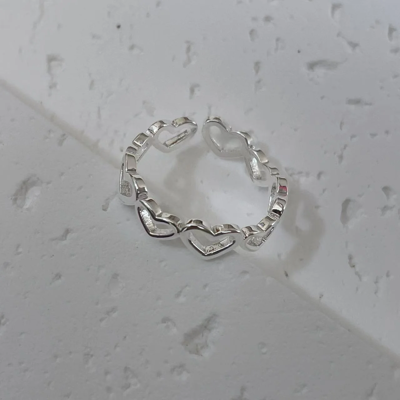 Silver-Plated Hollow Heart Ring tilted on white base