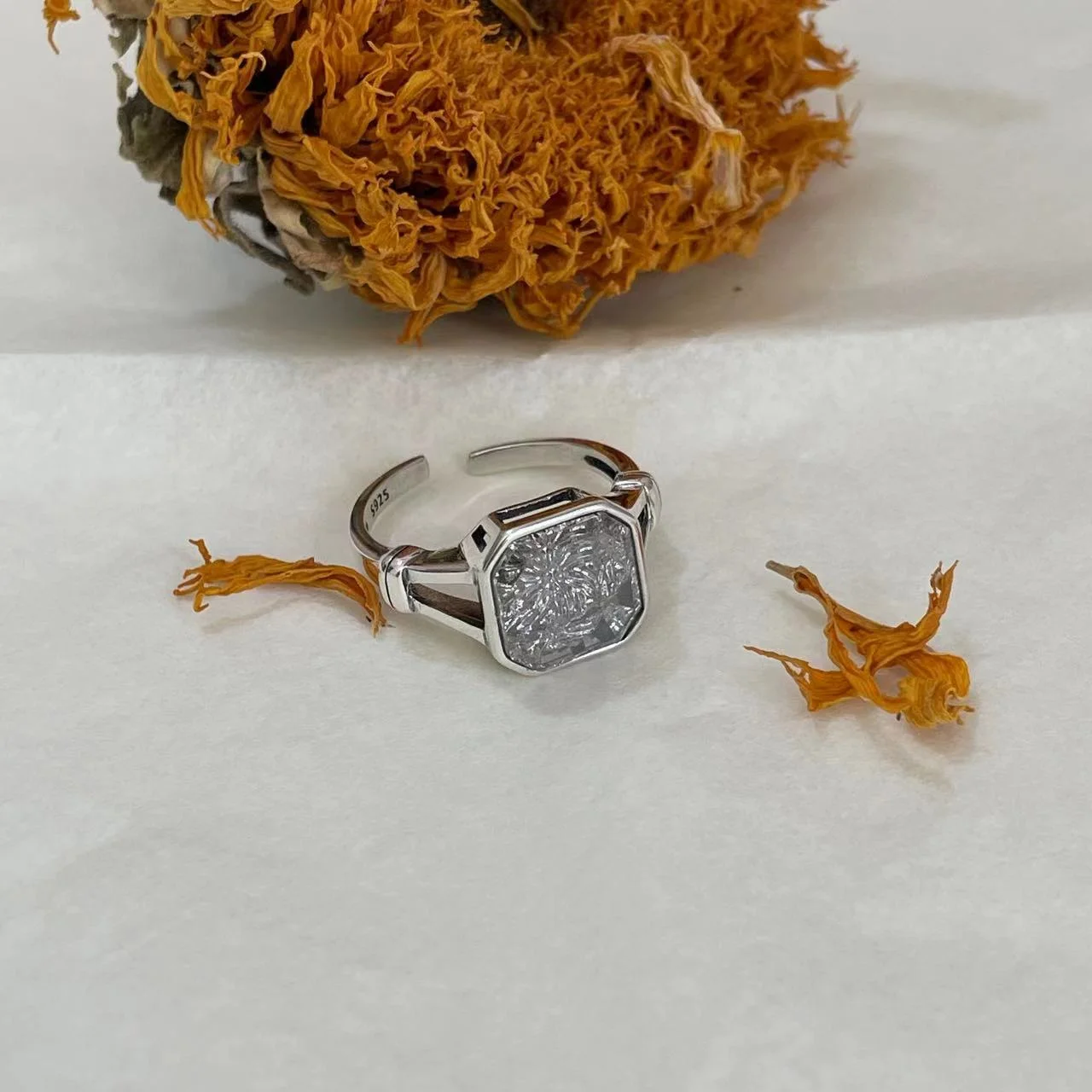 925 Sterling Silver White Topaz Ring on fabric with dried sunflower