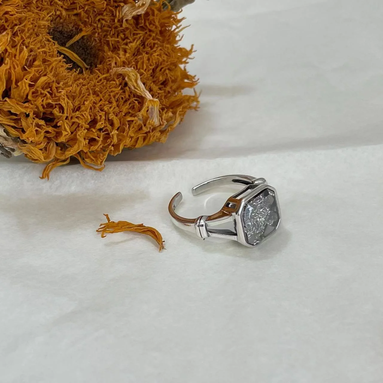 925 Sterling Silver White Topaz Ring sideways on fabric with sunflower