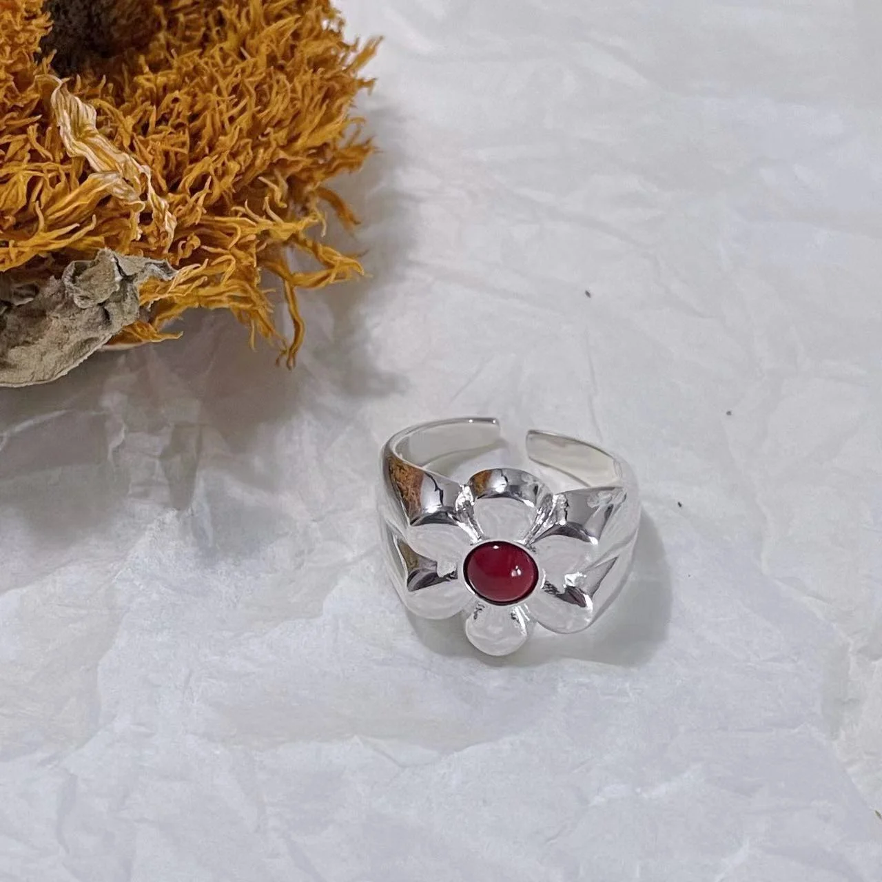 925 Sterling Silver Floral Ring with Red Natural Stone on White Fabric with a Dried Sunflower in the Background